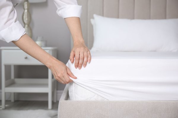 Woman,Putting,White,Fitted,Sheet,Over,Mattress,On,Bed,Indoors, Woman putting white fitted sheet over mattress on bed indoors, closeup