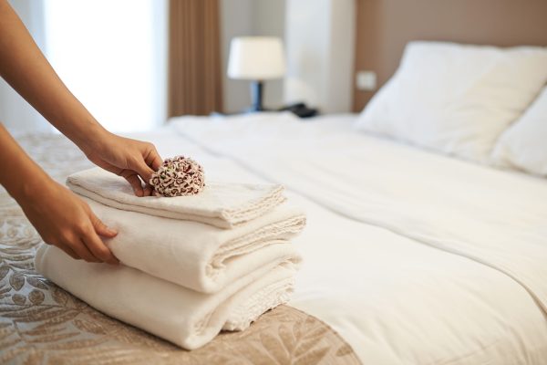 Hands,Of,Hotel,Maid,Putting,Flowers,On,The,Stack,Of Hands of hotel maid putting flowers on the stack of towels
